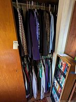 Closet filled with assorted jackets, coats, tops, and pants hung on hangers and some folded items.