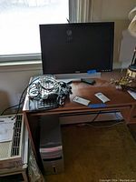 Photo of Dell monitor on a wooden desk along with a keyboard, mouse, and cables.