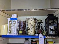 Photo of multiple decorative lanterns and candles on a shelf showing variety and condition.