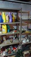 Metal shelving unit filled with various cleaning and household products in basement setting showing shelving structure and some surface wear.