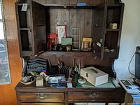 Wide view of wooden desk with cabinets showing various office supply items including staplers, file sorters, metal box, desk blotter, and pens.