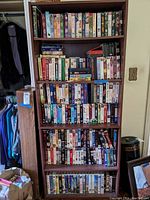 Full view of tall wooden bookshelf packed with multiple rows of VHS tapes.