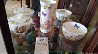 Three Ansley China Cottage Garden pieces including covered sugar bowl, vase, and bowls on glass shelf.