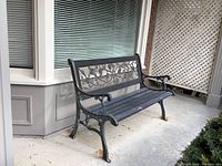Front-left angle showing the full steel frame and wooden slatted seat with rose design inlay in the backrest.