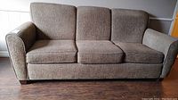 Front view of the brown 3-seat couch showing overall condition and shape.