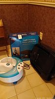 Photo of Dr Scholl O3 Pure Ozone Foot Spa and Carex Uplift Premium Power Lifting Seat with box beside wall on floor.