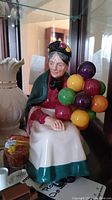 Front view of the Royal Doulton 'The Balloon Seller' figurine showing the detailed facial features, colorful balloons, and seated posture.