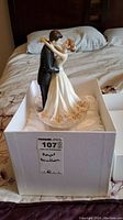 Full view of the Royal Doulton figurine standing in the box lined with satin fabric. Shows bride and groom in wedding attire with floral details on the bride's dress.