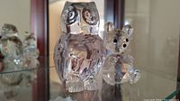 Photo showing the Swarovski bear and Princess House owl crystal figurines side by side on glass shelf.