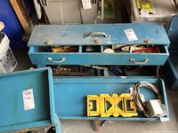 Photo showing large blue metal toolbox with compartments partially open, displaying the yellow miter box and electrical cords inside