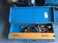 Overview of opened blue metal toolbox showing multiple hand tools inside and wooden tray