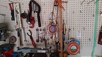 Wide view showing assorted hand tools mounted on pegboard including wrenches, pliers, ratchets, clamp, tubing.