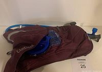 Maroon Camelbak hydration pack showing main compartment and hydration bladder with mouthpiece.