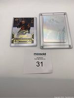 Front of Connor McDavid hockey card with gold scripted autograph error, showing Nathan MacKinnon autograph, in protective holder.