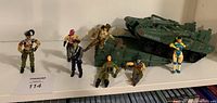 Seven G.I. Joe figures in front of and on green military tank vehicle, including winged figure and muscular figure with mohawk