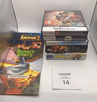 Stack of 3 Nintendo DS games complete in cases, 2 GBA games complete with original boxes, and 2 instruction booklets (Rayman 2 and Thunder Spirits) displayed to the side.