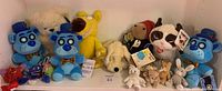 Front view of the lot showing all 15 mixed plush toys on a shelf, including four blue bears with top hats, a yellow lion, a white dog, a panda with a tag, and various small rabbits and mice.