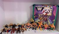 Lot of 17 mixed wrestling figures grouped in front of the new Grayskull wrestling ring box, showing front standing wrestlers and others lying down