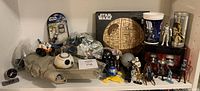 Full view of Star Wars memorabilia lot showing toys, action figures, cups, and model items arranged on shelves.