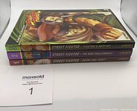 Three volumes of Street Fighter manga stacked showing spines, volumes 1, 2, and 3 with colorful spines and titles.