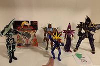 Five Yu-Gi-Oh figures displayed including one carded figure in original packaging showing wear and creasing on the card.