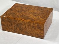 Closed humidor box showing burl wood veneer exterior with polished surface and detailed grain patterns.