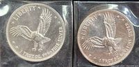 Obverse sides of two Liberty Eagle silver coins with eagle design and fine silver markings in protective sleeves.