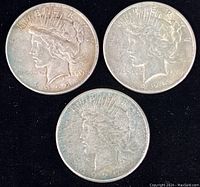 Obverse side of three Peace Silver Dollars dated 1922 and 1925, showing Lady Liberty profile with some wear.