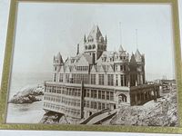 Close-up photo of print showing detailed view of 1902 Cliff House building on rocky coast in sepia tone.