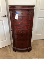 Front view of closed jewelry chest showing 7 curved drawers and decorative stenciling