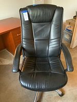 Front view of black leather executive desk chair showing padded seat and armrests with vertical stitching on upholstery.