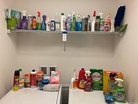Wide view of cleaning supplies on laundry room shelf and laundry surface showing sprays, boxes, and cleaning tools