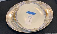 Three matching Limoges C. Ahrenfeldt serving platters stacked, showing gold handles on the smallest platter and decorative rims