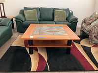 Photo of coffee table in living room setting with couches and rug visible.