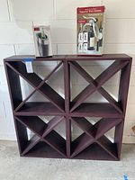 Wooden wine cabinet with eight angled compartments next to boxed wine cooler and boxed tabletop wine opener