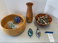 Photo showing two wooden bowls (one large light wood with horizontal carving, one smaller patchwork), wooden vase, two ceramic duck figurines, and decorative glass spheres inside the large bowl.