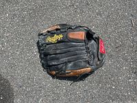 Photo of the front side of a black and brown Rawlings baseball glove showing yellow Rawlings logo, creased and worn leather.