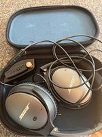 Bose wired over-ear headphones inside a black padded carrying case with lid open, showing exterior of ear cups and Bose logo.