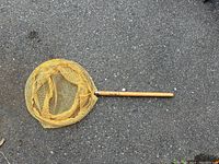 Yellow butterfly net with wooden handle on pavement