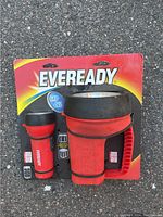 Photo shows two red Eveready LED flashlights, one small handheld and one large spotlight style, both unused in original packaging.