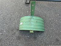 Green metal hose holder on pavement showing mounting bracket and ribbed design.