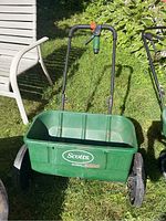 Front view of green Scotts AccuGreen 3000 spreader with black wheels and handle.