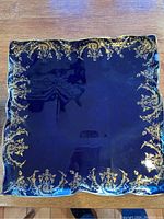 Full view of the square blue serving plate with gold decorative edging, displayed on a wooden surface.