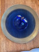 Top-down view of the blue and gold serving plate showing the entire round plate with gold ornate rim and blue center with handle.