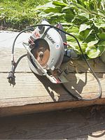 Top view of Skil circular saw on a wooden surface outdoors, showing blade and power cord details.