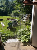 Two metal conical tomato cages leaning against a door frame with garden background.