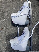Top view of one white women’s figure skate showing the laces, metal eyelets, and blade.