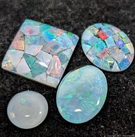 Four genuine opal stones on black cloth background showing two mosaic style opal triplets and two solid cabochon opals with distinct shapes and color play.