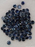 Loose sapphires spread on a flat surface showing their faceted round cuts and color variations.