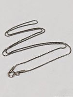Sterling silver chain necklace laid out fully extended to show length and clasp.